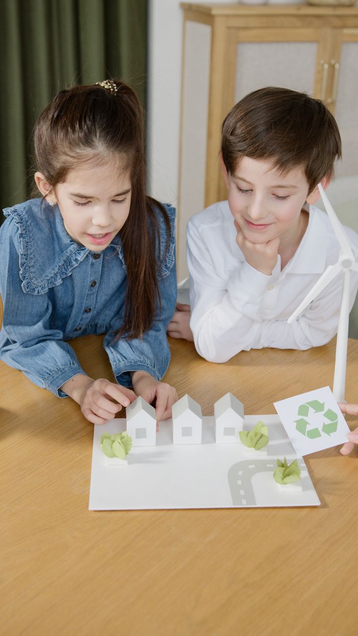Initiatives Kids explore renewable energy with a scale model featuring a wind turbine.